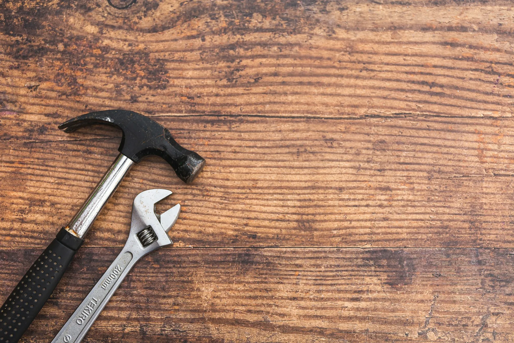 Hammer and adjustable wrench on a wooden surface